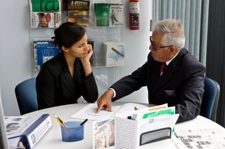 A young adult woman at the Church employment resource service center in Mexico City, Mexico.  A senior male missionary is helping her.