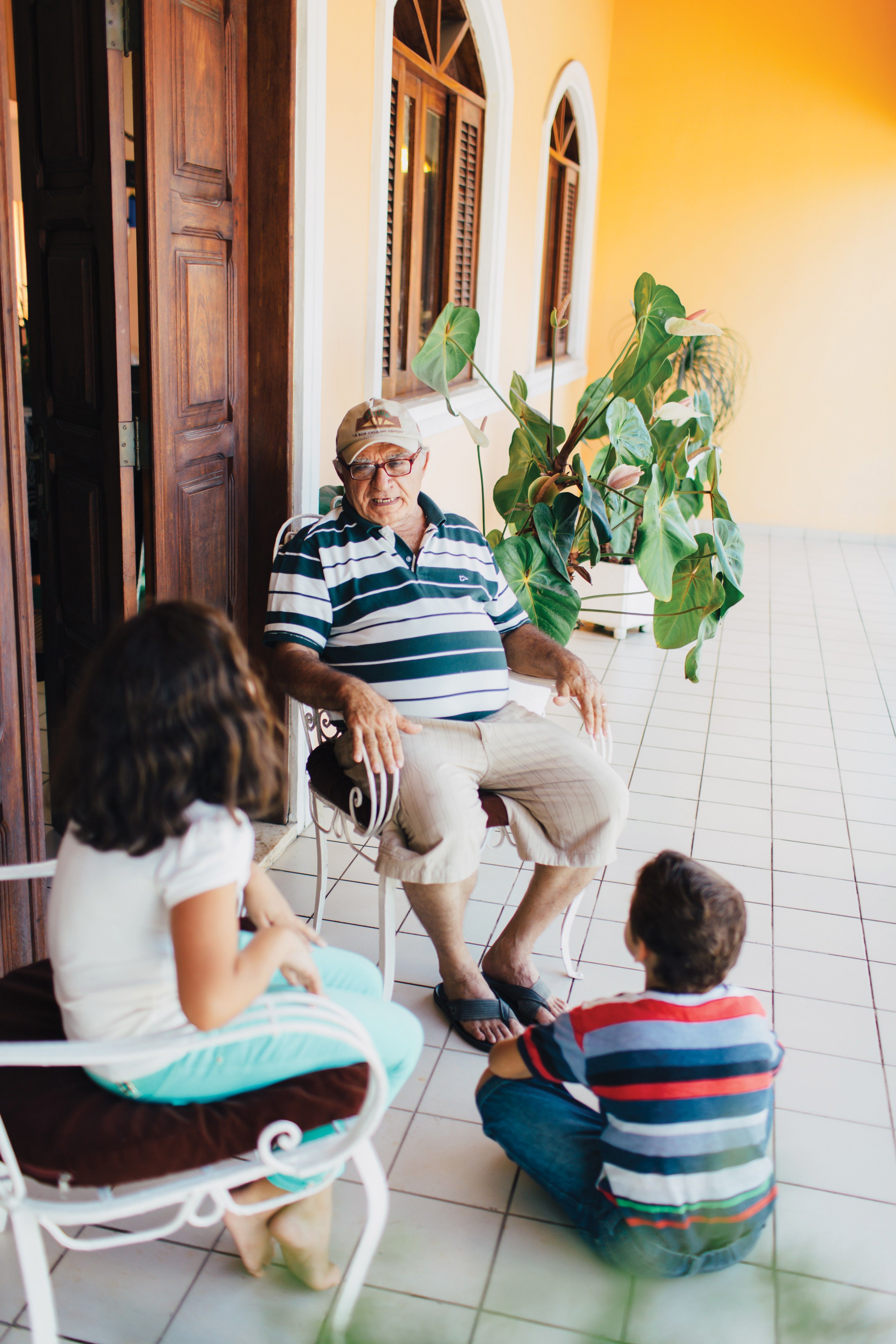A man sitting outside in Brazil and talking with his two grandchildren.