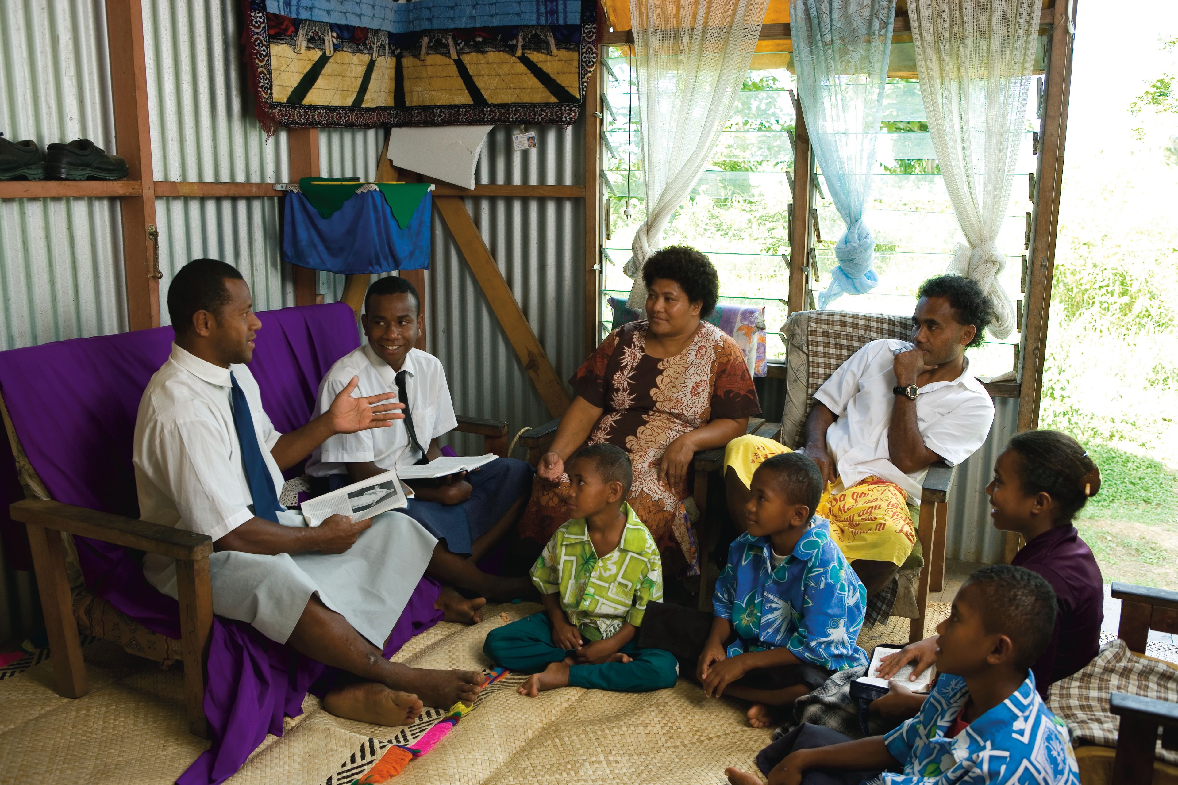 Elder missionaries teaching a family of six from Tonga.