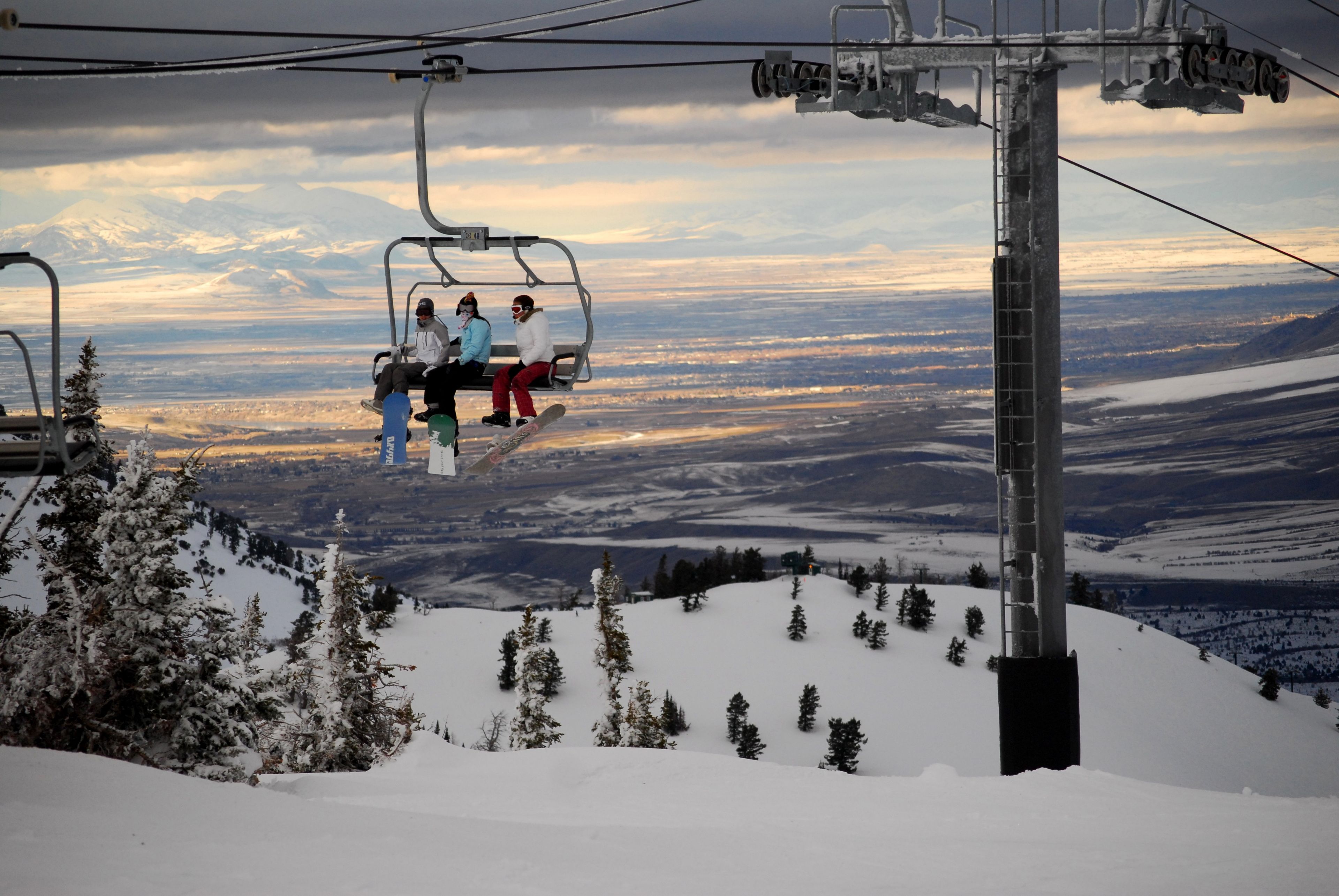 Snowboarders ride the ski lift up the mountain.