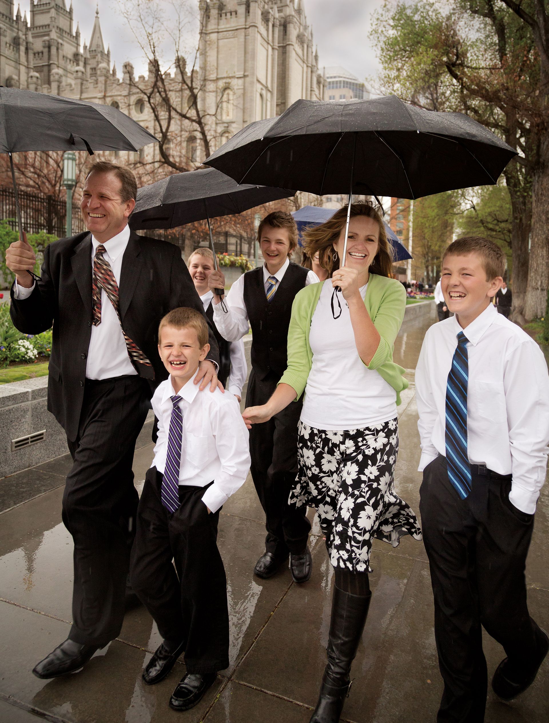 A family holding umbrellas as they walk through rain to the Conference Center.
