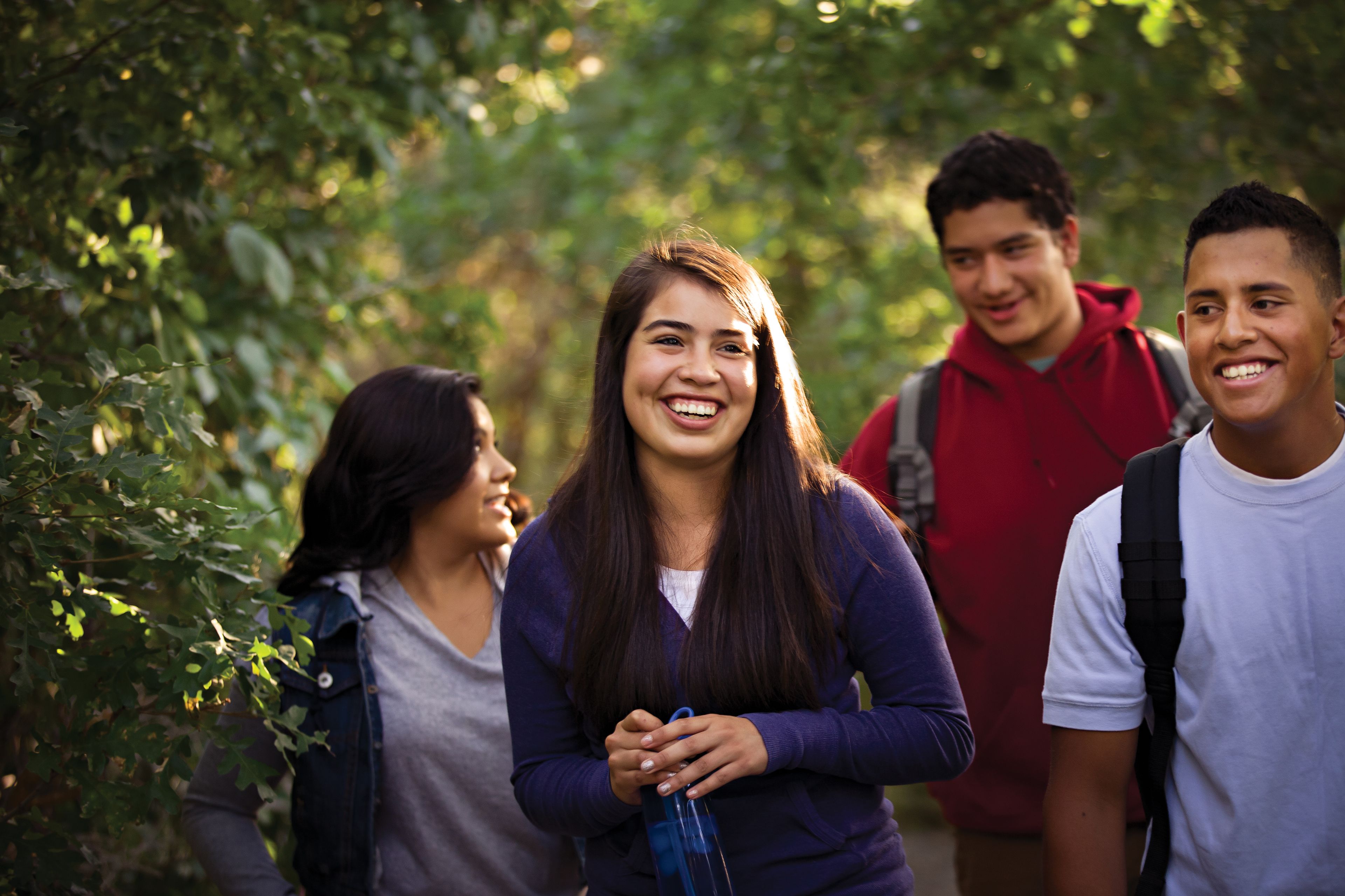 Two teenage couples hiking outside together.