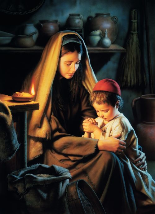 Jesus Christ depicted as a child with his mother Mary. Christ is kneeling beside Mary and resting His clasped hands on Mary's lap. Mary has her head bowed as she and the young Christ pray. There is an oil lamp burning on a table next to the mother and son.