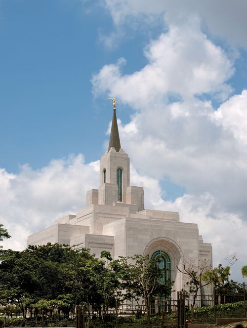 A partial view of the San Salvador El Salvador Temple, with a view of some windows, the spire, and trees on the grounds around the temple.