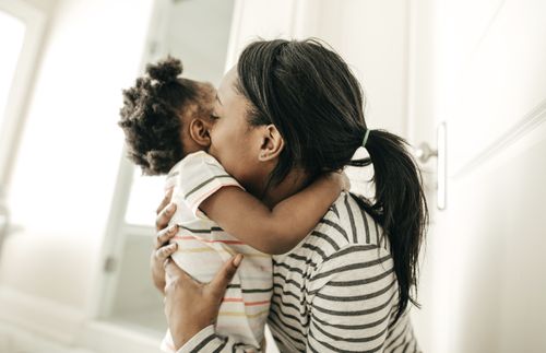 mother hugging and kissing her toddler daughter