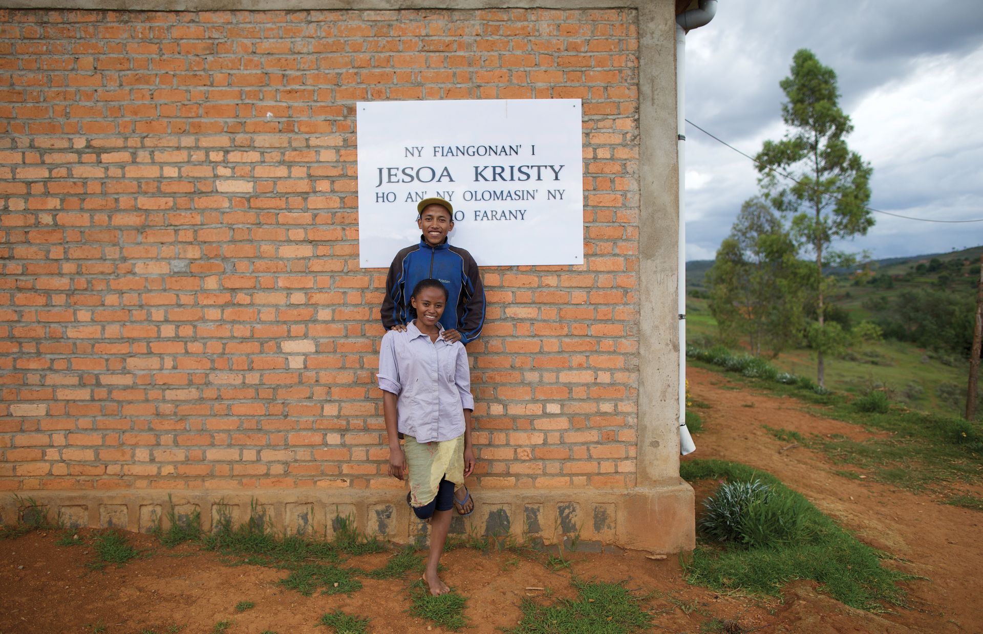 Rakotomalala and Razafindravaonasolo stand in front of the new chapel in Sarodroa. This chapel, made of concrete and brick, was built by the members.