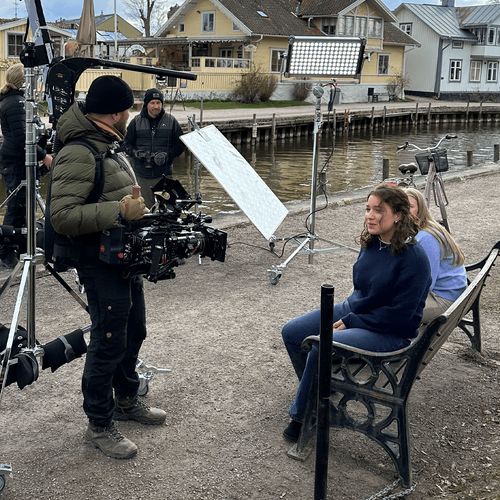 man filming young women on a bench