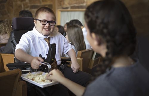 boy in a wheelchair passing the sacrament