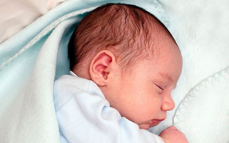 Un recién nacido dormido envuelto en una manta