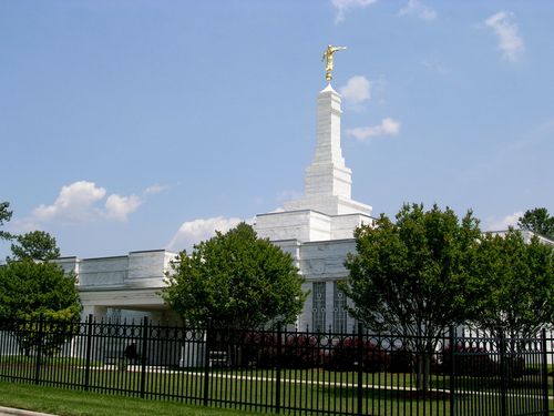 The entire Raleigh North Carolina Temple, with trees and bushes on the grounds within the fence.