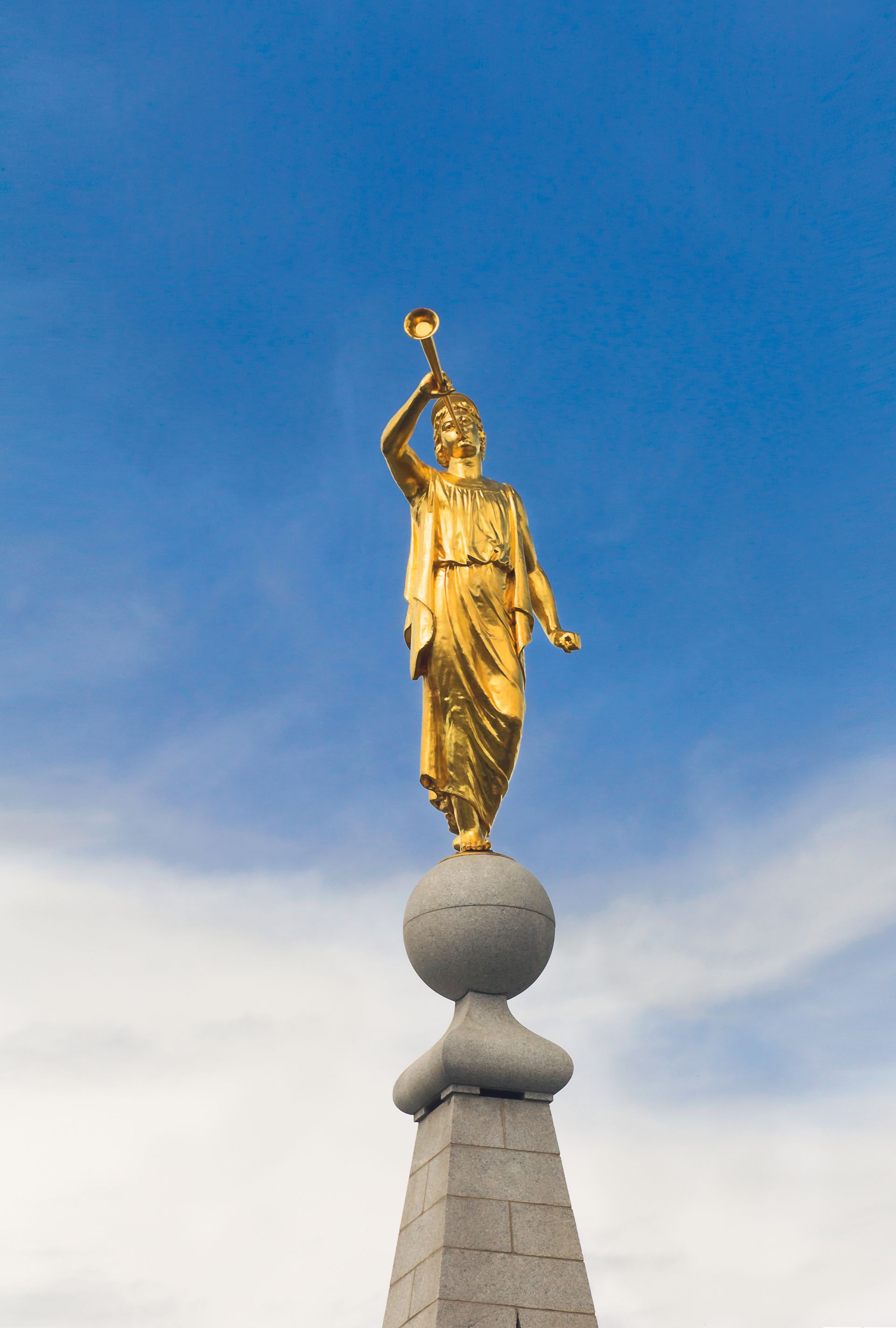 A photograph of the angel Moroni atop the Salt Lake Temple on a partly cloudy day.