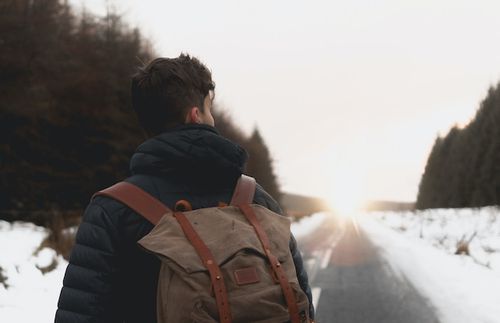 Man wearing a backpack walking down a road