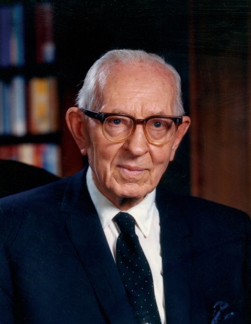 President Joseph Fielding Smith sitting in his office, wearing a white shirt, a dark suit, a dotted tie, and glasses.