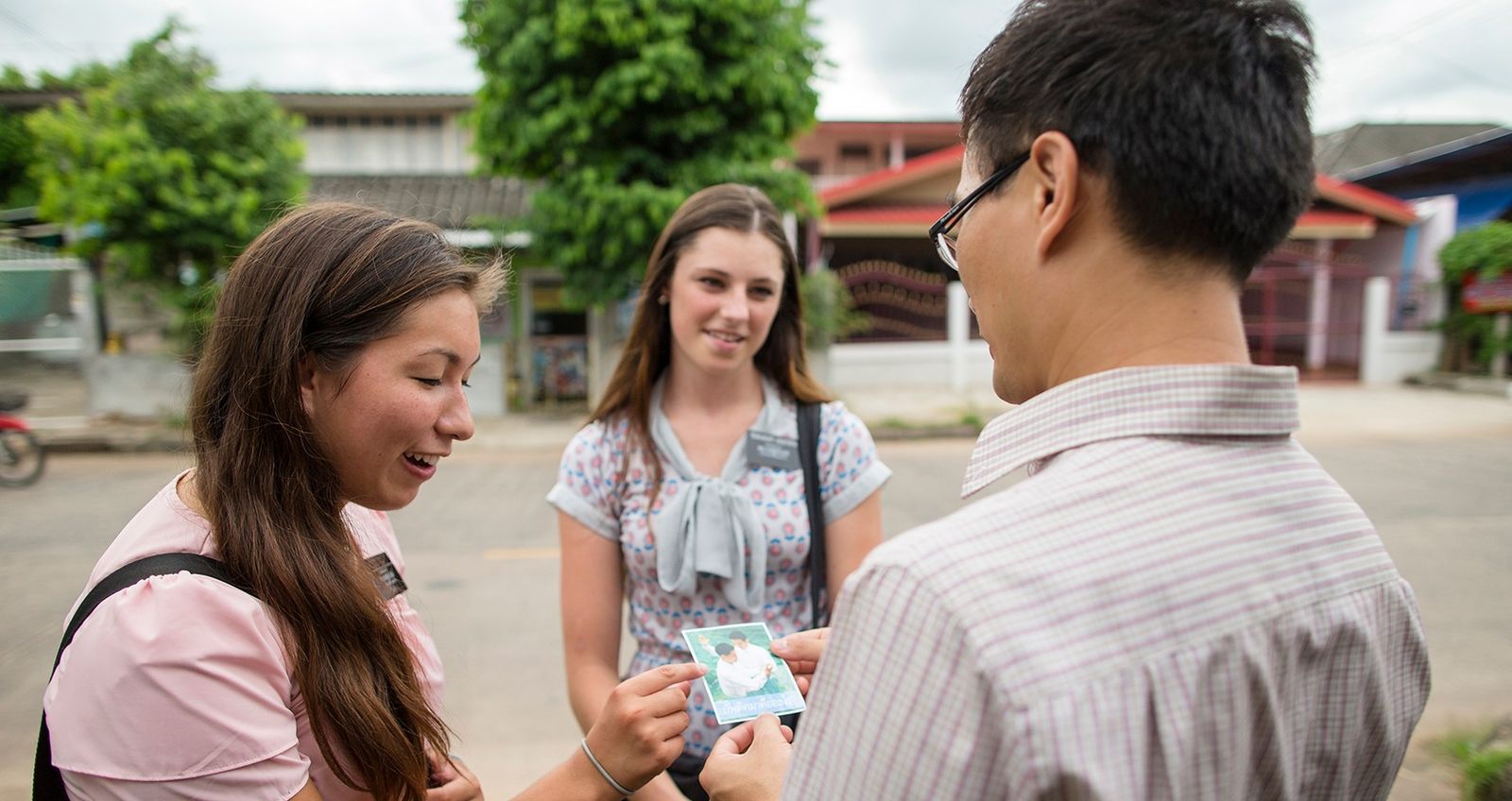 Elder and Sister Missionaries in Thailand riding their bikes, talking to people and having a meeting.