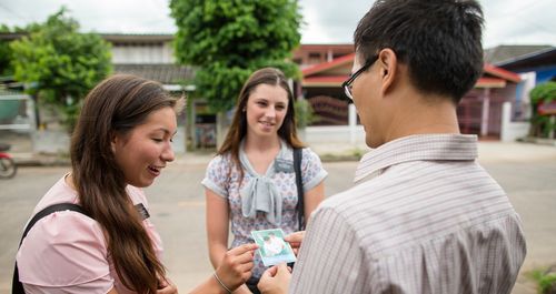 Elder and Sister Missionaries in Thailand riding their bikes, talking to people and having a meeting.