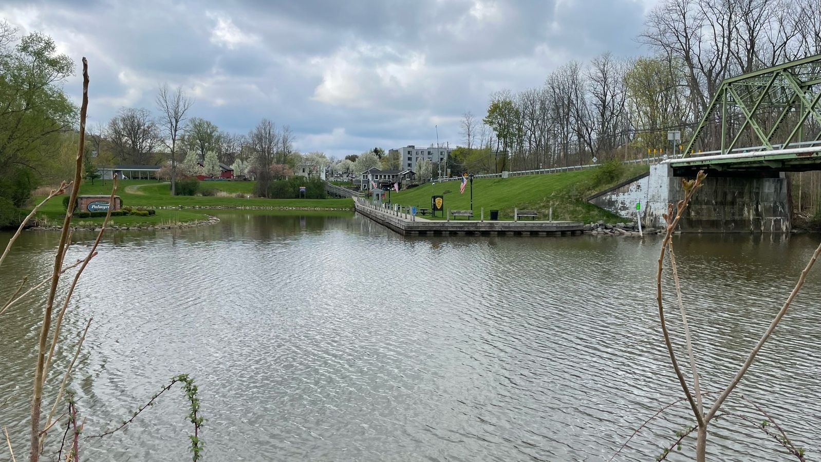 View of a canal from the banks, the nearby city is visible in the background. 