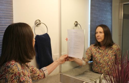 woman looking at list posted on mirror