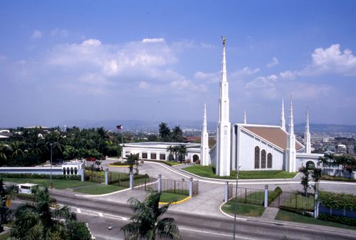 A view of the Manila Philippines Temple and grounds from across the street, with a few white clouds overhead.