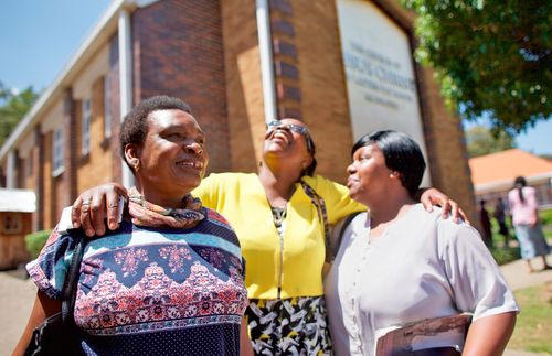 three South African women in front of meetinghouse