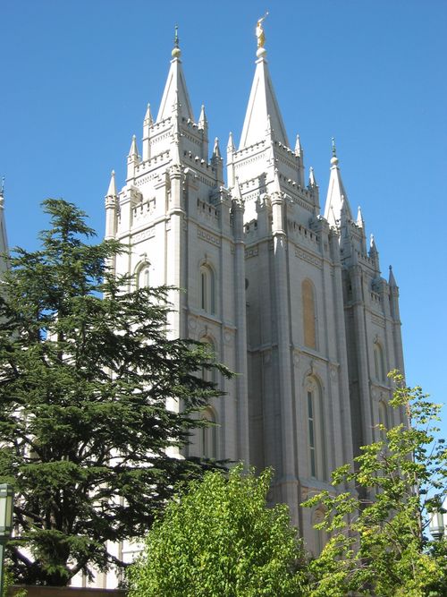 The front three spires of the Salt Lake Temple rising above the trees on the grounds of the temple.