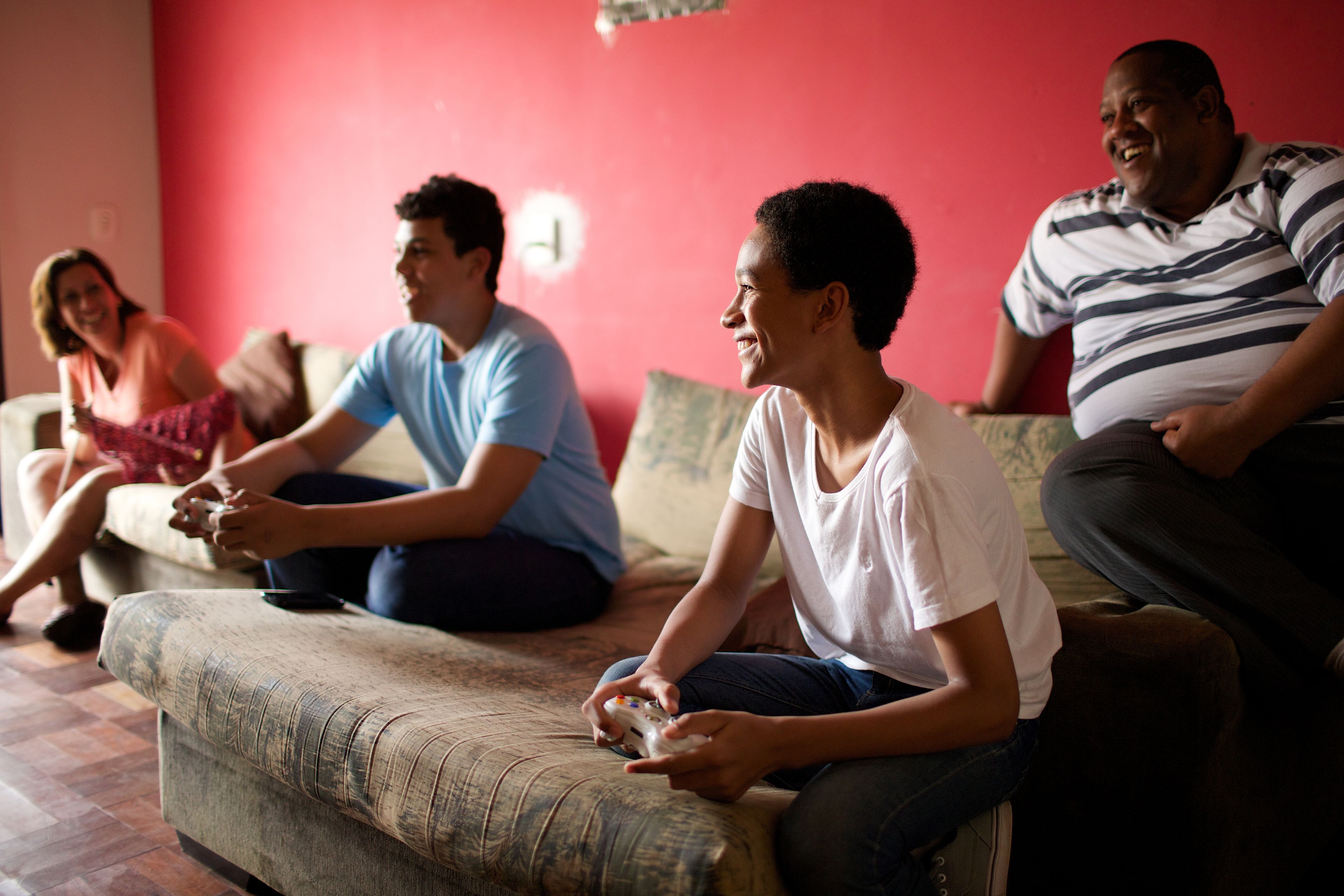 A mother, father, and two sons play video games at home.  
