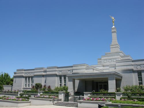 The Melbourne Australia Temple exterior entrance and grounds with flowers, on a sunny day.