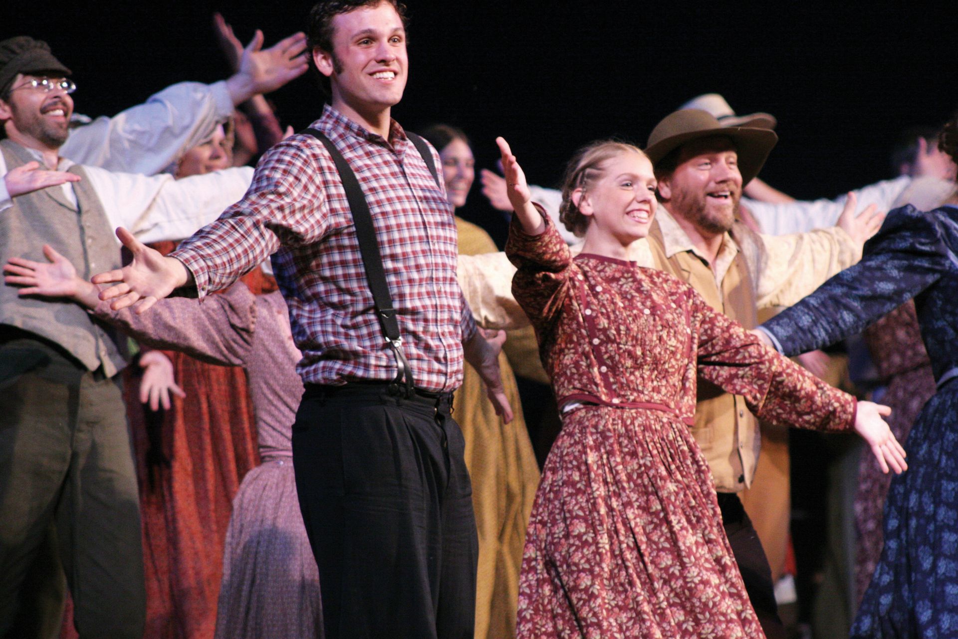 Actors and actresses from the Nauvoo Pageant smile with open arms.