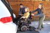 Girl in wheelchair being helped into car