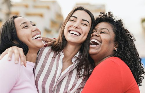 Drei Frauen stehen zusammen und lachen
