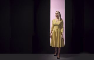 woman standing in a dark room with a lit doorway