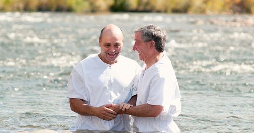 man baptizing another in a lake