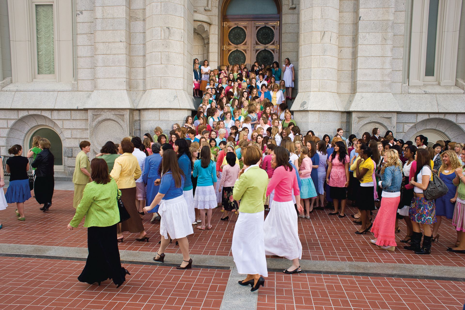 A large group of young women and their leaders standing on the Salt Lake Temple stairs.