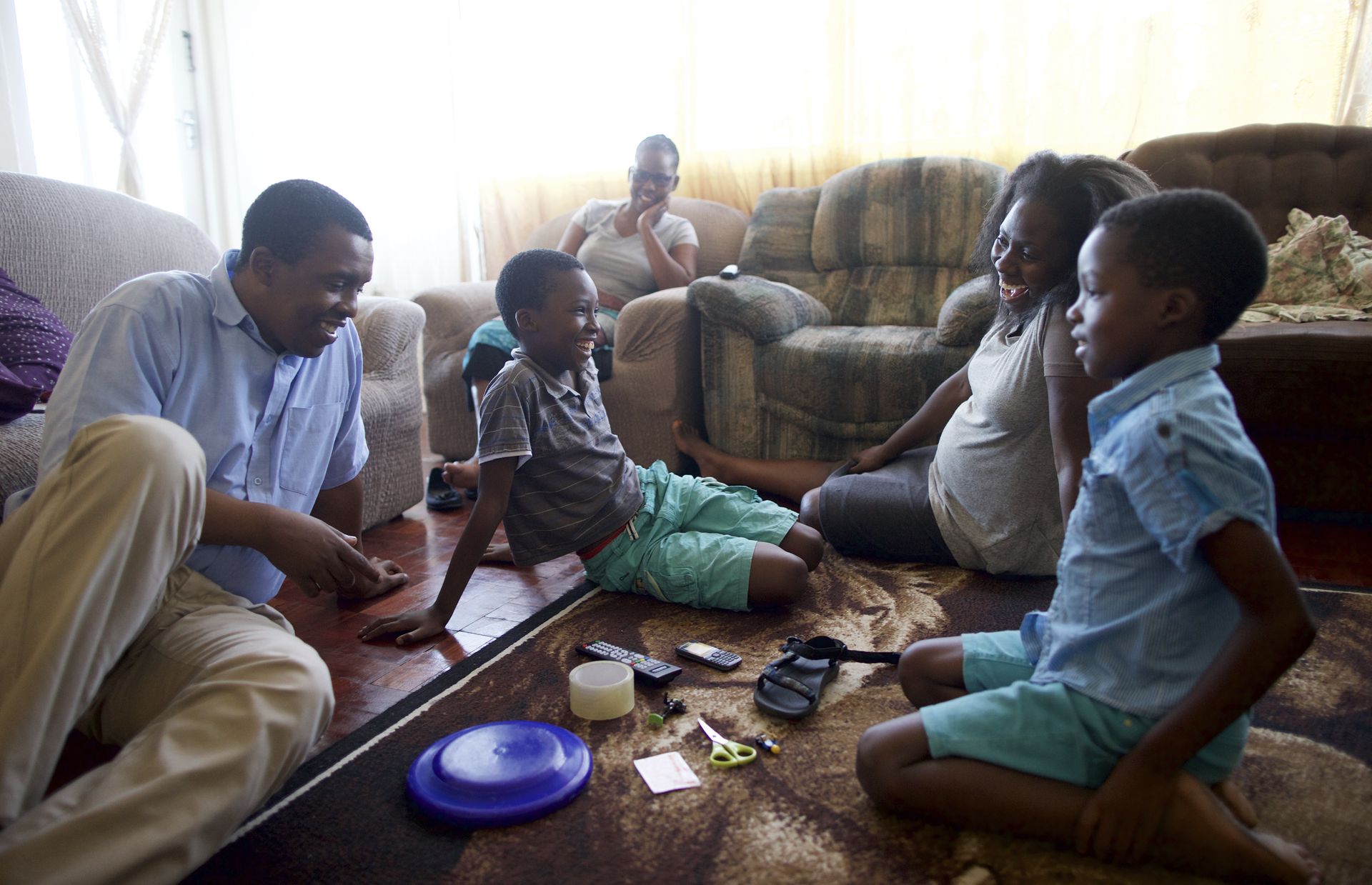 South Africa.  Family spending time together playing a memory game.  Boy about to guess what is missing.