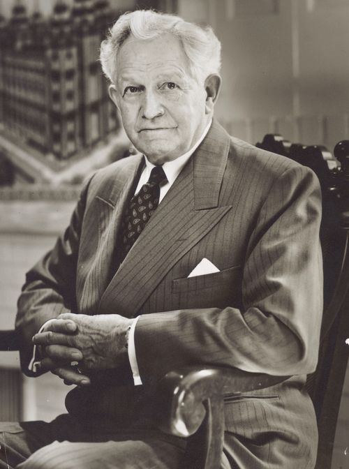 A portrait photograph of David O. McKay in a pinstriped suit, sitting in a wooden chair.