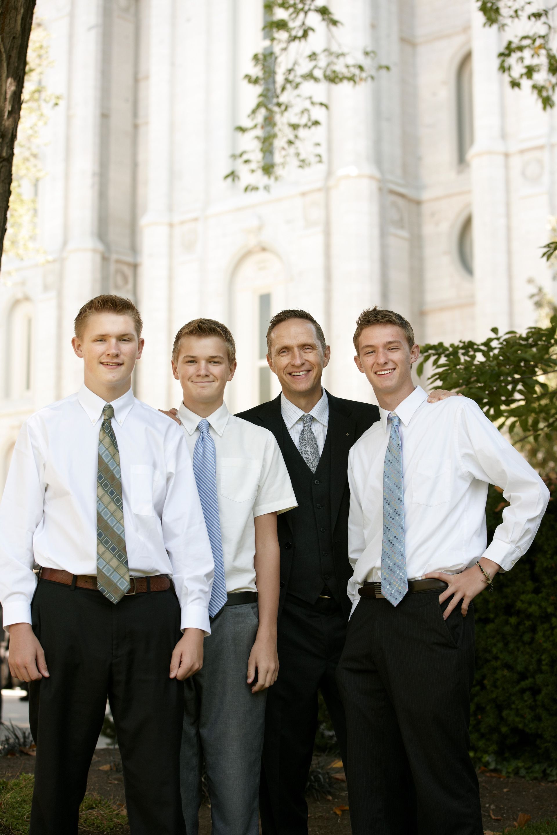 A man and three young men standing outside the temple, waiting for a session of general conference.  