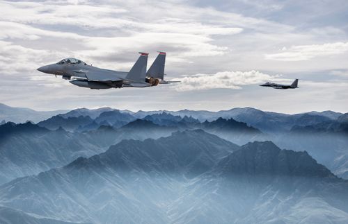 fighter jet flying over mountains