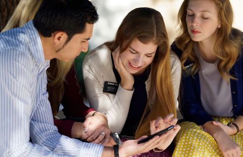 des sœurs missionnaires et un couple regardent un téléphone