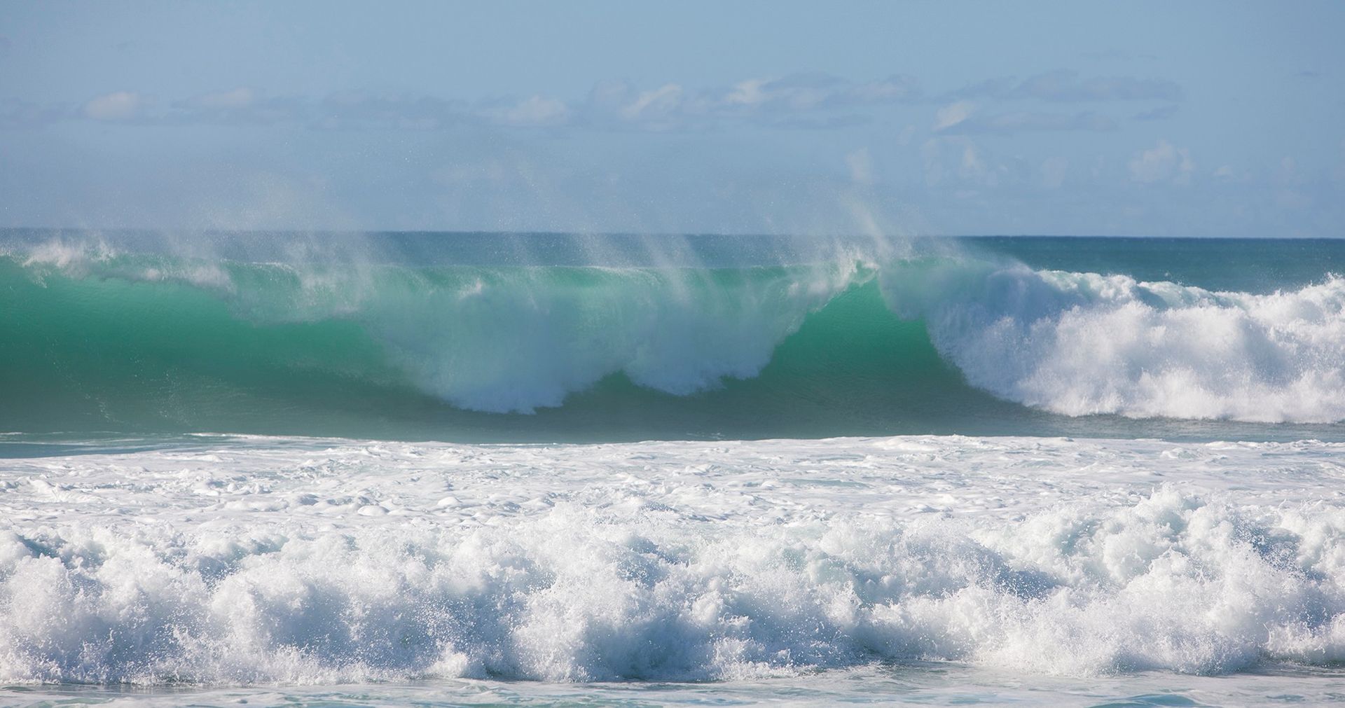 Daytime photo of waves crashing on a beach.