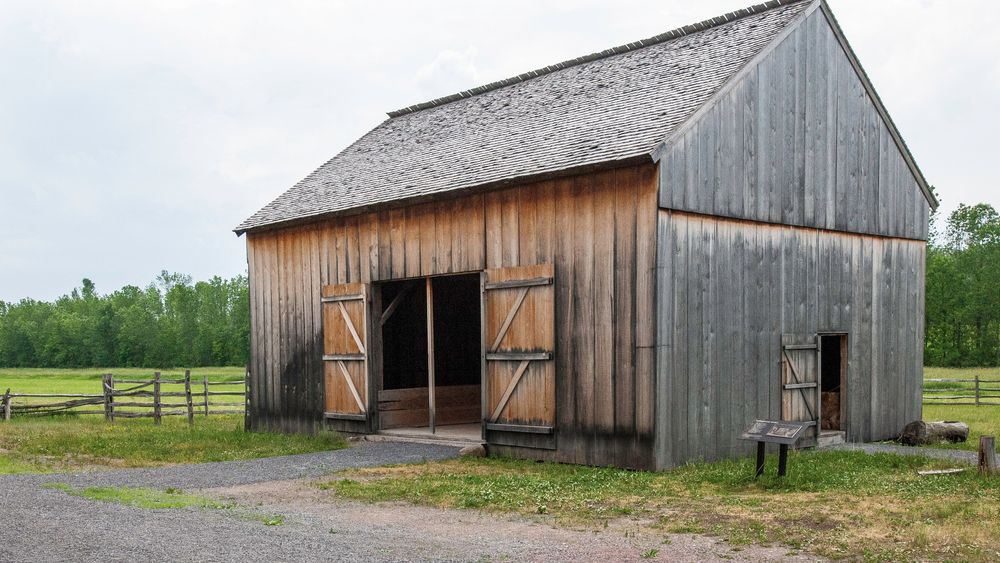 A large wooden barn with the doors wide open on the property of the Smith family farm in Palmyra, New York.