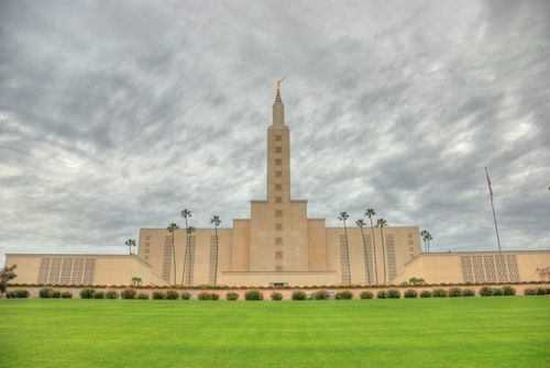 The front of the Los Angeles California Temple on a stormy day, with a green lawn in the foreground.