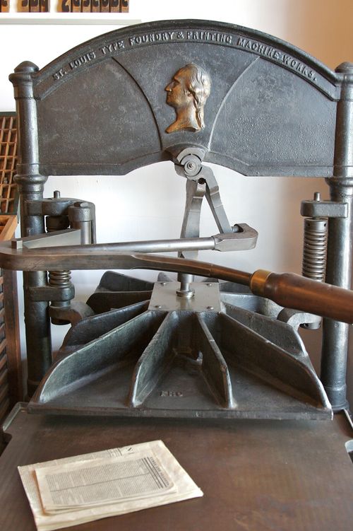 An image of an antique silver printing press with a booklet next to it at the Nauvoo print shop in Illinois.