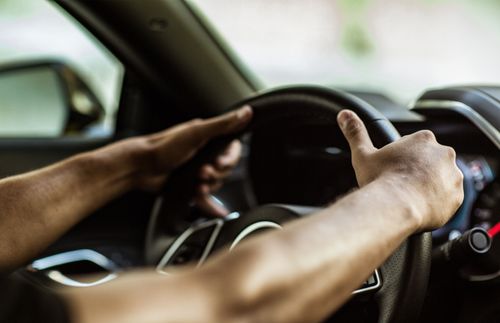 hands holding the steering wheel of a car