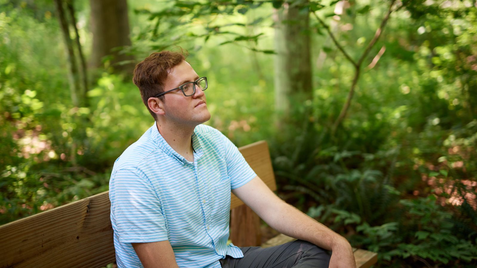 A couple sits on a bench in the woods at the Priesthood Restoration Site near Susquehanna Depot, Pennsylvania.
They are surrounded by trees.