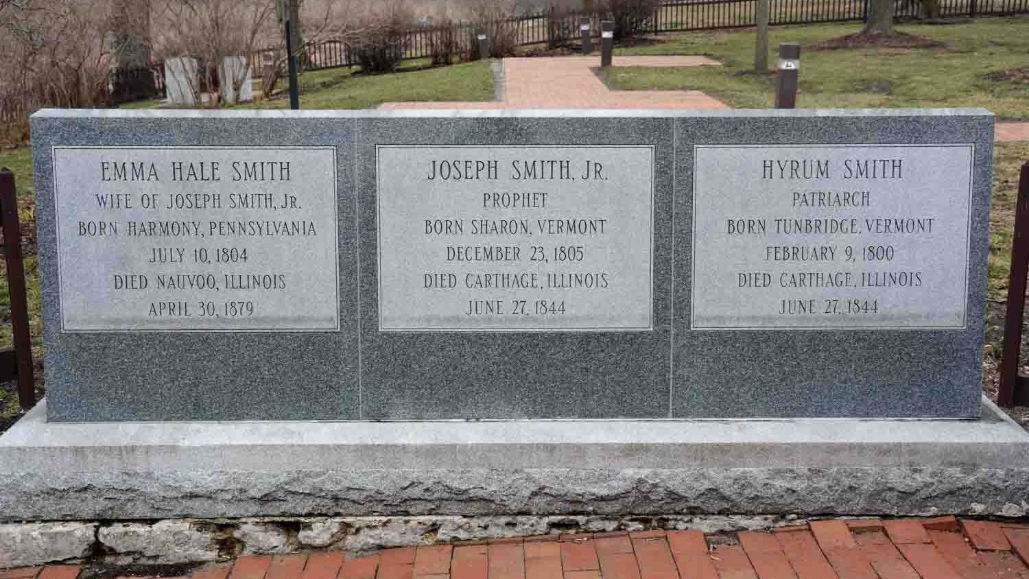 Dark gray, granite memorial gravestones for Emma Hale Smith, Joseph Smith Jr., and Hyrum Smith.  