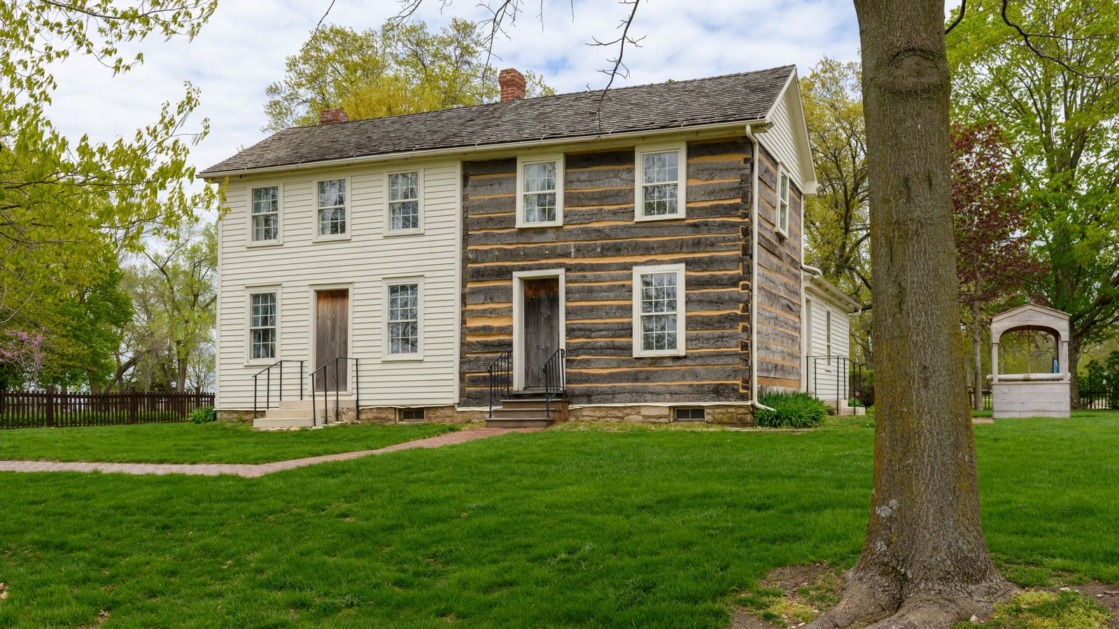 The expanded Smith Family Homestead building which is half log home and half white-painted frame home.