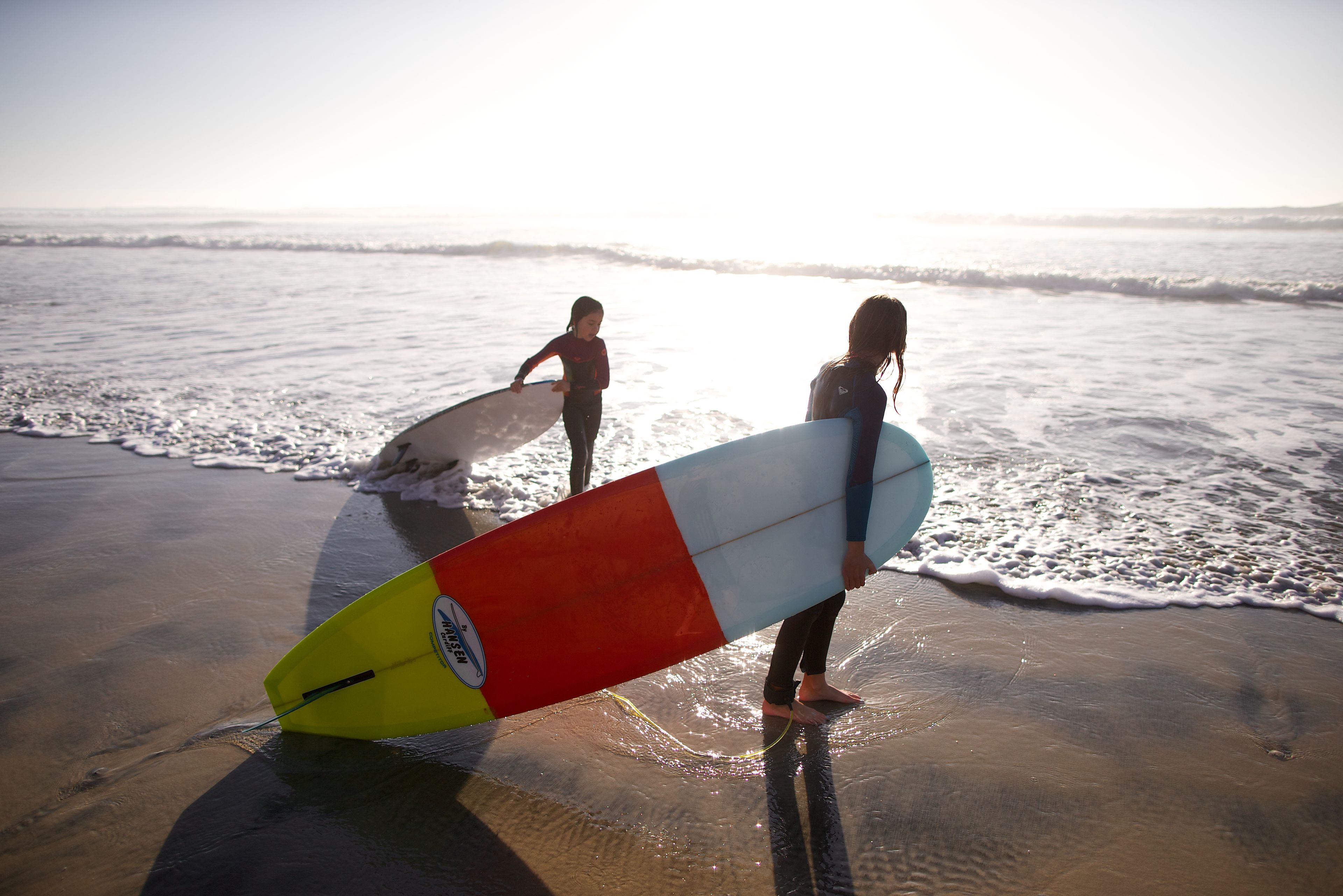 Two girls surf together.