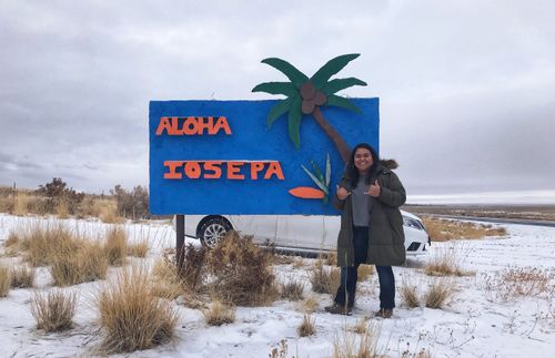 the author standing in front of a sign that says “Aloha Iosepa”