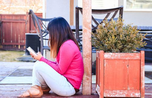 a woman sitting outside and looking at a phone