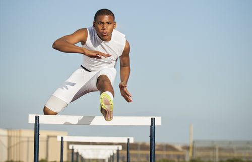 young man running hurdles