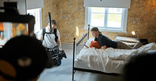 man filming young man using a phone on his bed